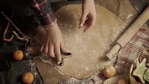 Close-up of a woman's hand making gingerbread cookies in the form of a Christmas tree and a gingerbr