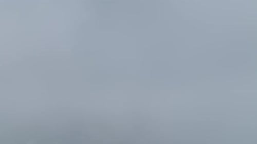 Vue aérienne : nuages qui roulent sur les sommets des montagnes et une forêt sombre en contrebas