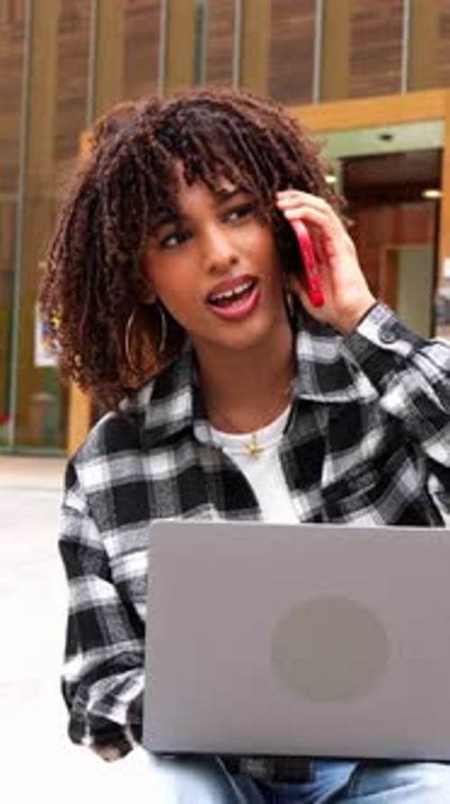 Young Adult Using Laptop and Talking on Phone