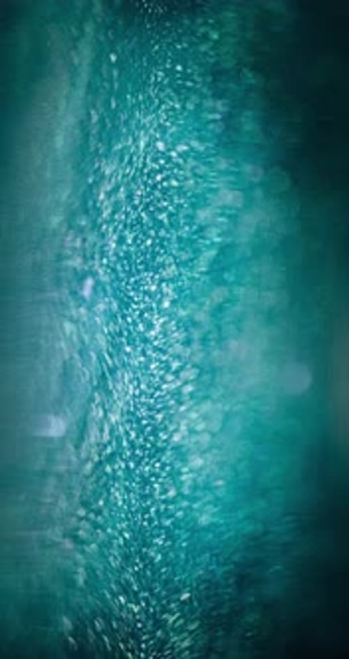 Sparkling Green-Blue Particles Glimmer Vertically