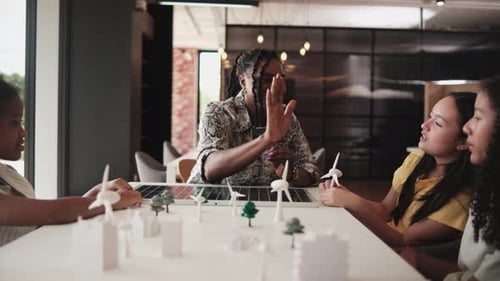 Teacher shows students model city with wind turbines