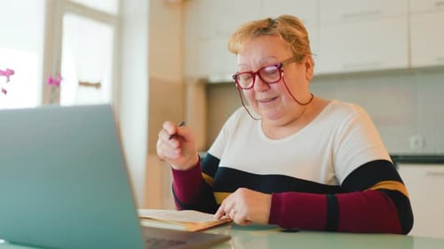 Woman Talking with Laptop at Kitchen Table
