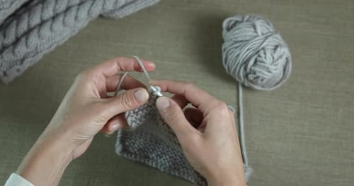 Hands Knitting Gray Yarn on Needles Close Up