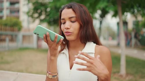 Woman Sending Voice Message on Mobile Device Outside