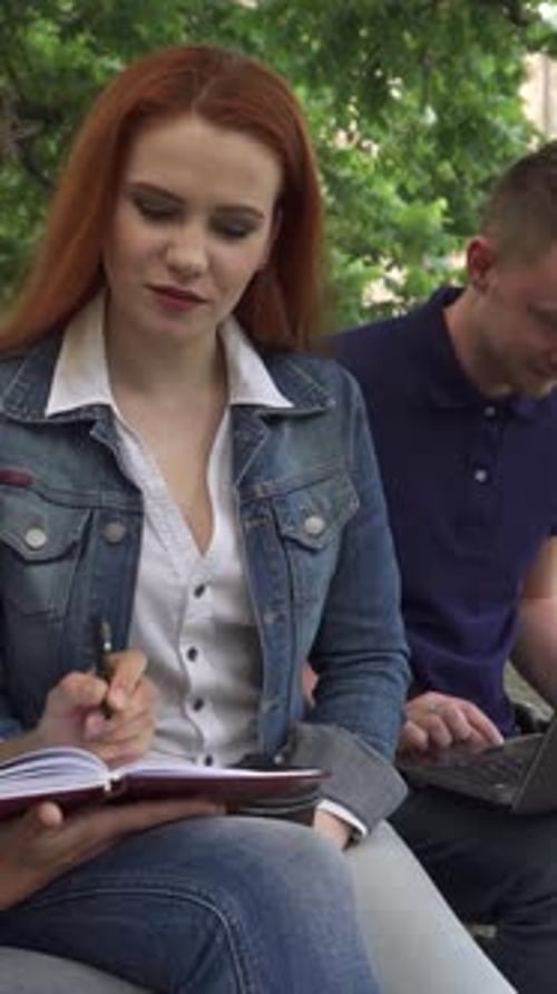 Estudantes engajadas colaboram no campus enquanto um cara estuda nas proximidades