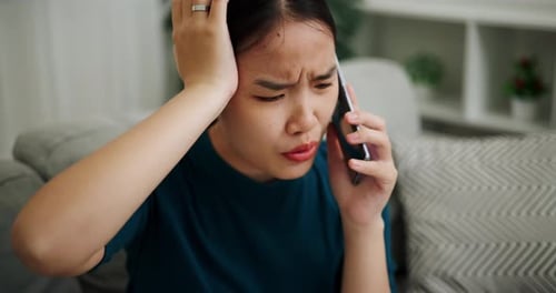 Worried Young Woman Talking on Smartphone at Home