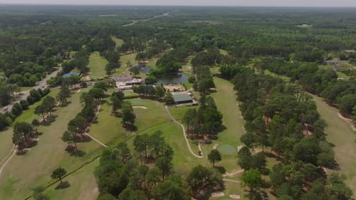 Aerial Views of a Vast Golf Course Surrounded By Lush Forests and Buildings in the USA Showcasing