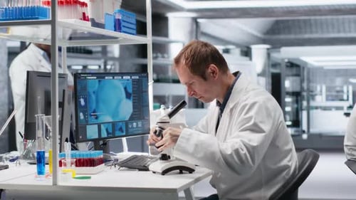 Male Science Expert Operates with Microscope and Laboratory Tray