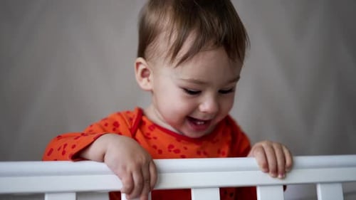 Adorable Infant Playing in a White Crib