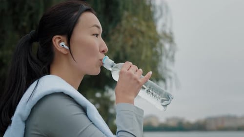 Fit Woman Drinks Water After Exercising Outdoors