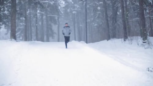 Man Jogging in Snowy Forest During Winter Day