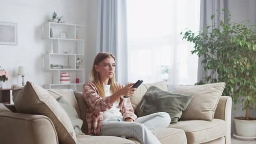 Young Woman Relaxes, Channel Surfing on Sofa