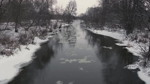 Winter Morning River with Flowing Ice and Snowy Banks