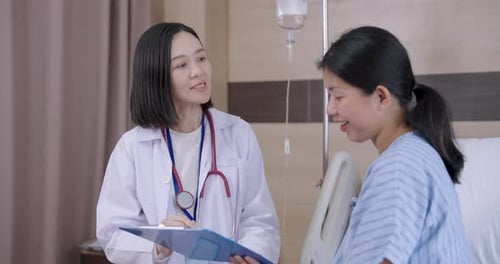 Asian female doctor talking to asian female patient during medical consultation session in hospital