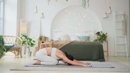 Adult Does Stretching in Bright Bedroom
