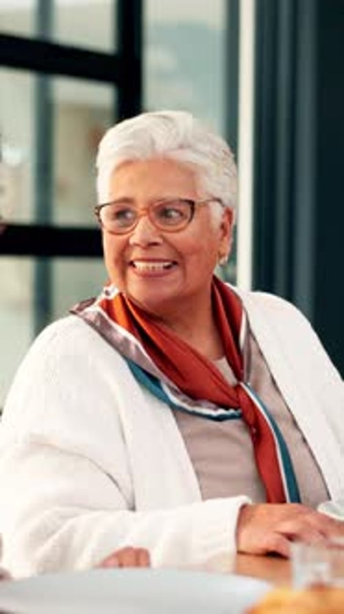 Smiling Senior Woman Sitting at Table Indoors