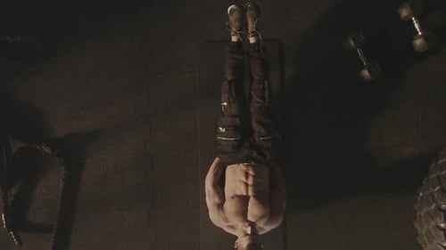 Muscular Man Does Leg Lifts in Gym, Overhead View