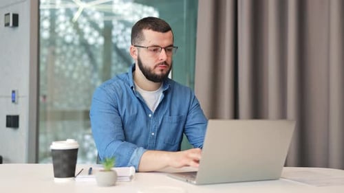 Focused Professional Working Diligently on Laptop in Modern Office
