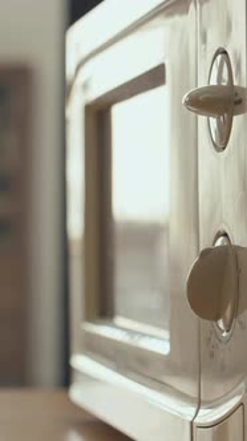 Hand Turning a Dial on Microwave Oven