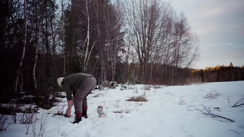 Man Carries Log Through Snowy Winter Landscape