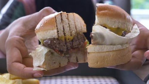 Hand Holding Beef Burger on Table Close Up