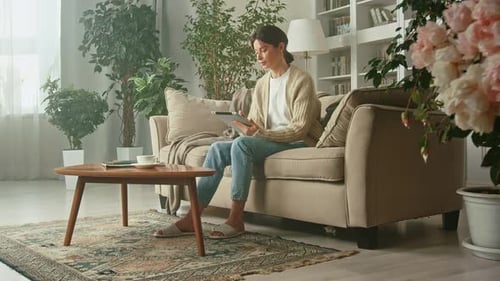 Young beautiful woman typing tablet in her apartment.