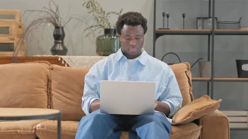Young Adult Types on Laptop on Brown Couch