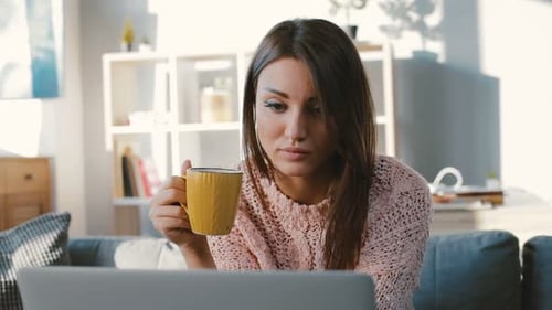 Woman relaxing with coffee and laptop at home