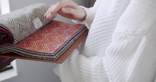 Woman Inspecting Colorful Fabric Samples in a Swatch Book