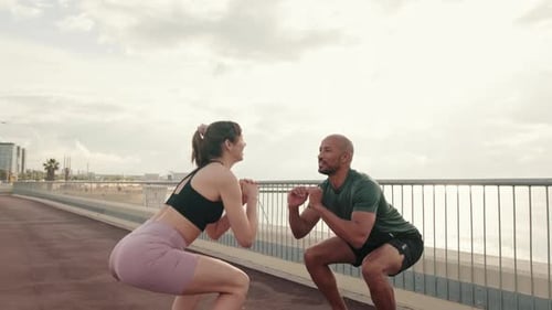 Couple Exercising Together by the Beach Doing Squats