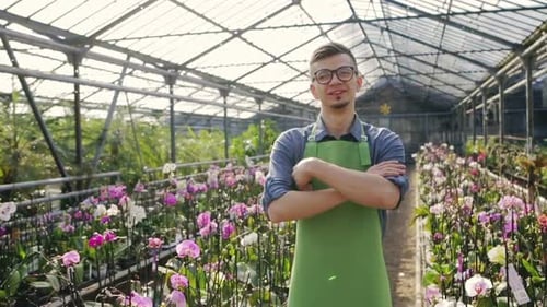 Gardener Smiling in Greenhouse with Orchids