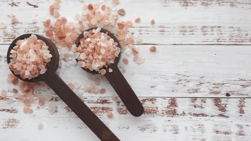 Close Up of Pink Rock Salt in a Wooden Spoon on Table