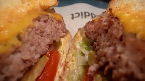 Tasty Juicy Hamburger in Fast Food Restaurant Closeup View of Cut Burger with Beef Cutlet