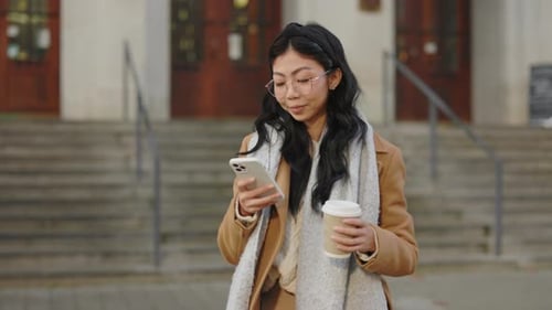 Smiling woman with phone and coffee in city