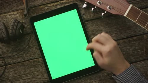 Musiker verwendet Tablet-PC mit Greenscreen im Portrait-Modus. Ansicht von oben. Kausaler Lebensstil