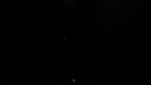 Submerge Collection: A round stone dropping from the top creating bubbles in the way on a black back