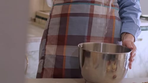A female baker prepares cupcake batter, sprinkling flour on the table. Home-baked goods, small busin