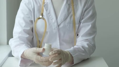 Doctor With Pills Pours Medication in Gloved Hand