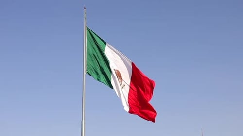 Steady footage of the mexican flag moving with the air at a sunny afteroon in the Mexico City Zocalo