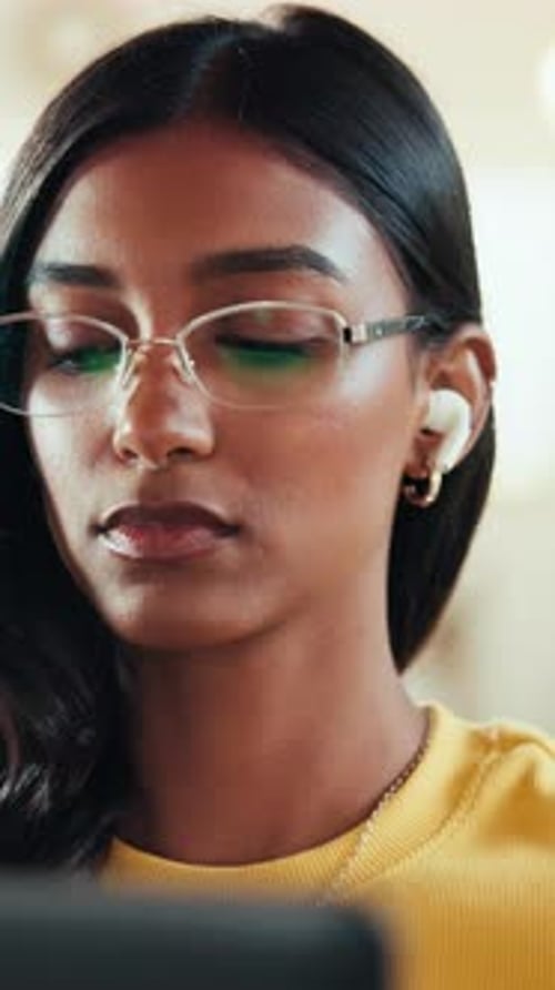 Young Woman Puts on Glasses and Wireless Earbud