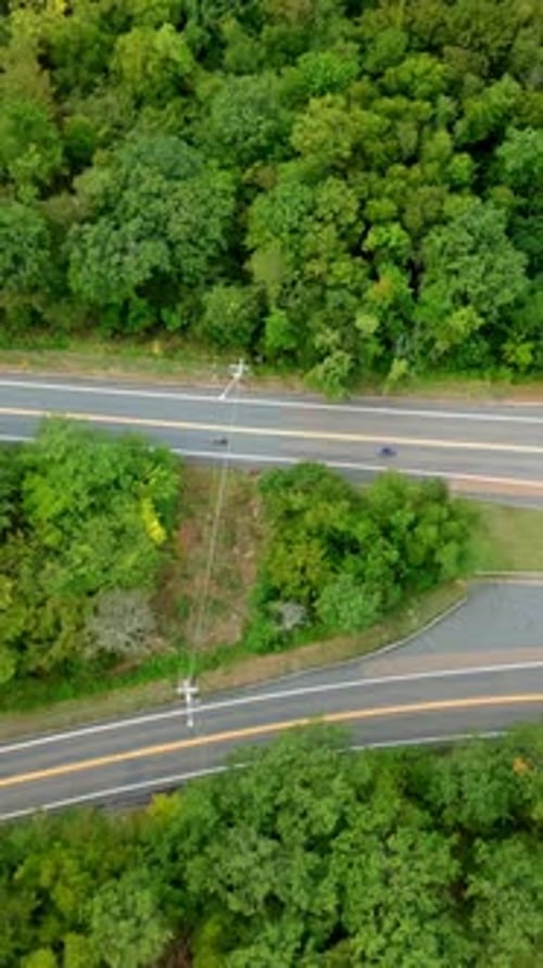 Aerial vertical view of winding road through dense forest in Berkshires, Massachusetts, with a car