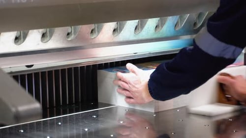 Worker Cutting Paper Using Paper Cutting Machine in a Printing Factory