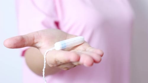 Steriler medizinischer Tampon für Frauen, der die Hand hält und ein Damenhygiene-Produkt gegen Unschärfe präsentiert