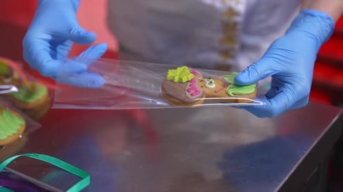 Packaging the ready-made sweets into plastic bags. Confectioner puts cookie of mushroom-shape