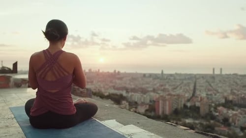 Junge Frau im Body praktiziert Yoga bei Sonnenaufgang am Aussichtspunkt