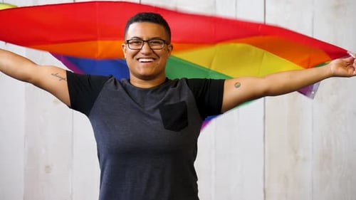 Smiling Adult Waving Pride Rainbow Flag Indoors
