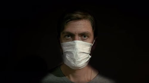 Man in Mask Stares Forward in Dark