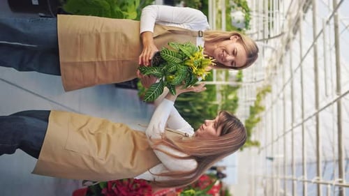 Two Women Examine Plant at Retail Greenhouse