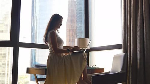 Woman Uses Laptop in Bright Urban Apartment