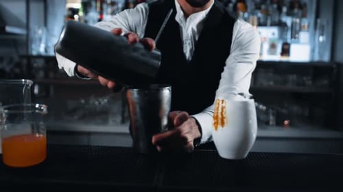 tracking shot of a bartender pouring a drink from a Boston shaker to another